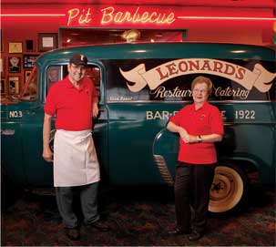 Older couple standing in front of small business