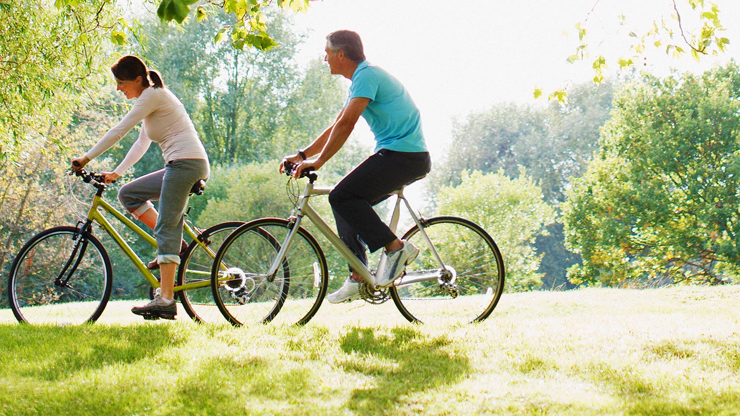 Man and woman riding bikes in park