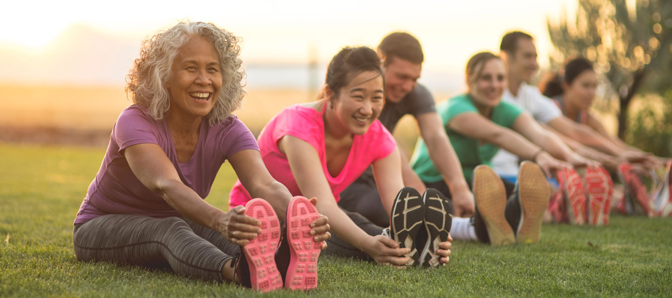 Group sitting on grass stretching for exercise 