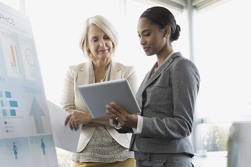 two women talking and looking at a tablet