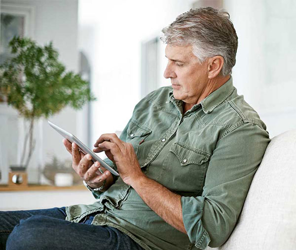 Hombre usando una tablea para enviar dinero con Zelle