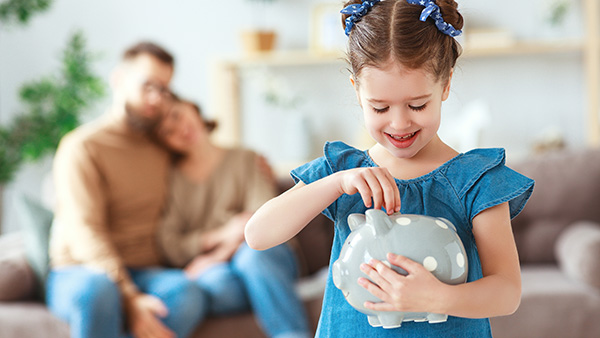 girl putting money into a piggy bank