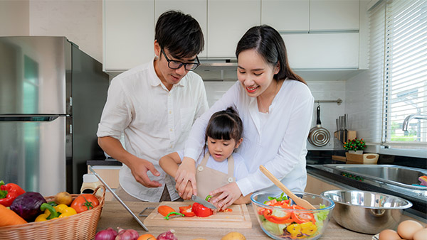 padres asiáticos ayudando a su hija pequeña en la cocina