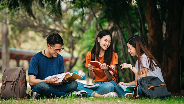 three asian friends studying in the park
