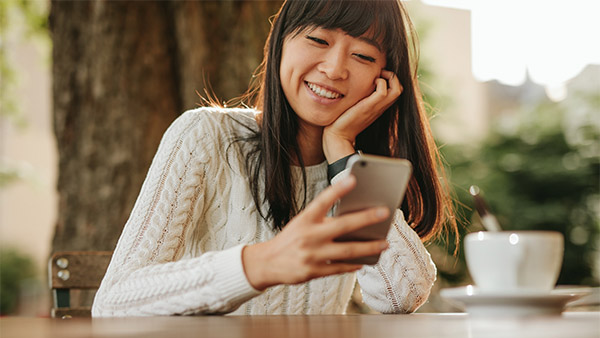 young asian woman in a cafe looking at her phone