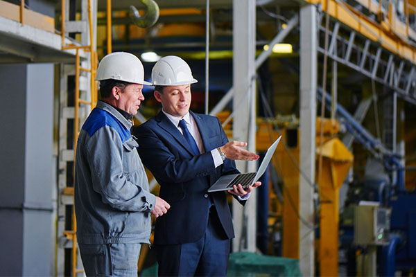 dos hombres con cascos blancos mirando una tablet