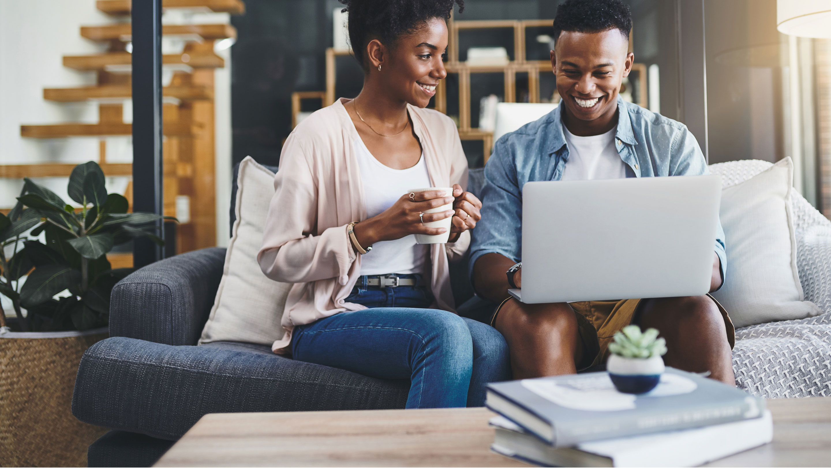 Pareja sentada en sofá mirando la pantalla de una laptop