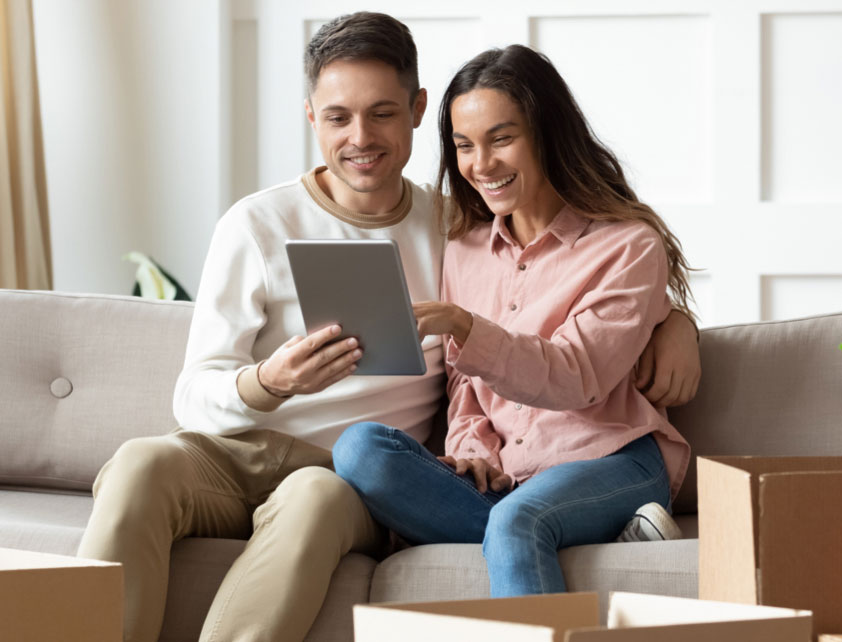 Pareja sentada en sofá mirando la pantalla de una tablet