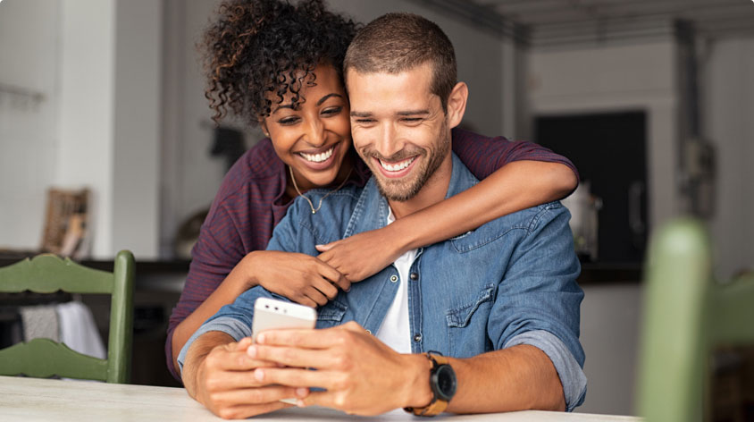 Couple smiling looking at smartphone