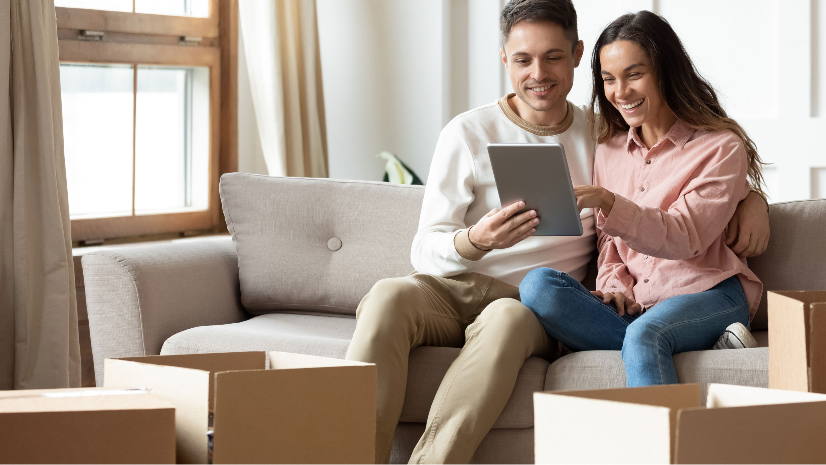 Pareja sentada en sofá apuntando a la pantalla de una tablet