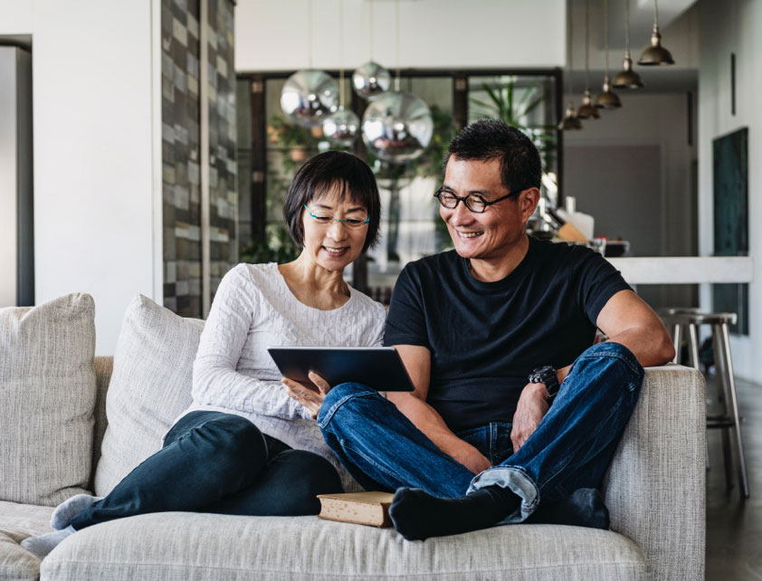 Pareja sentada en sofá mirando la pantalla de una tablet