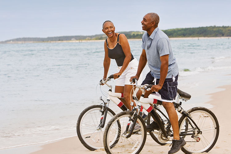 older couple riding bicycles on the beach