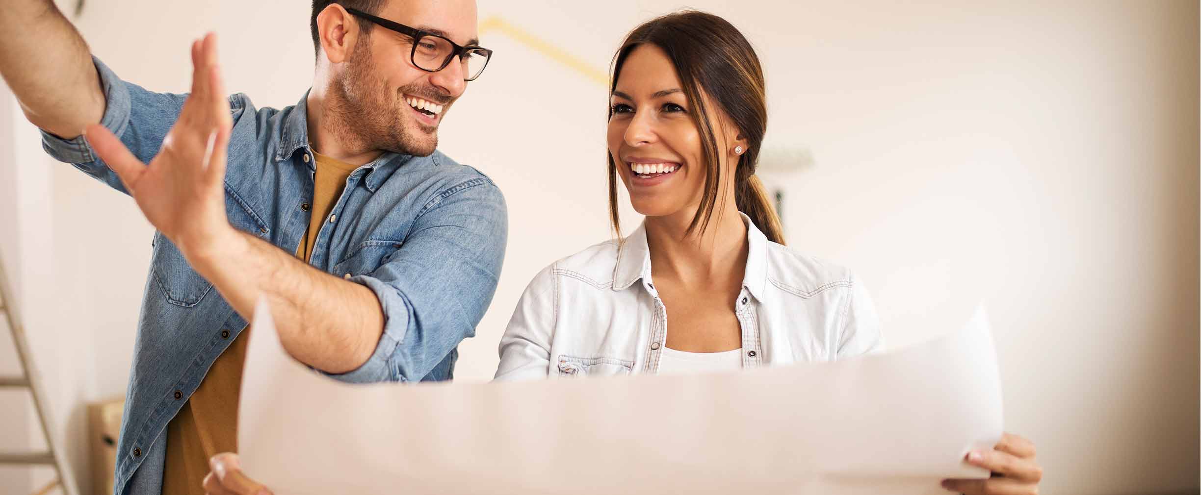 Pareja joven de pie en su apartamento planificando una renovación.