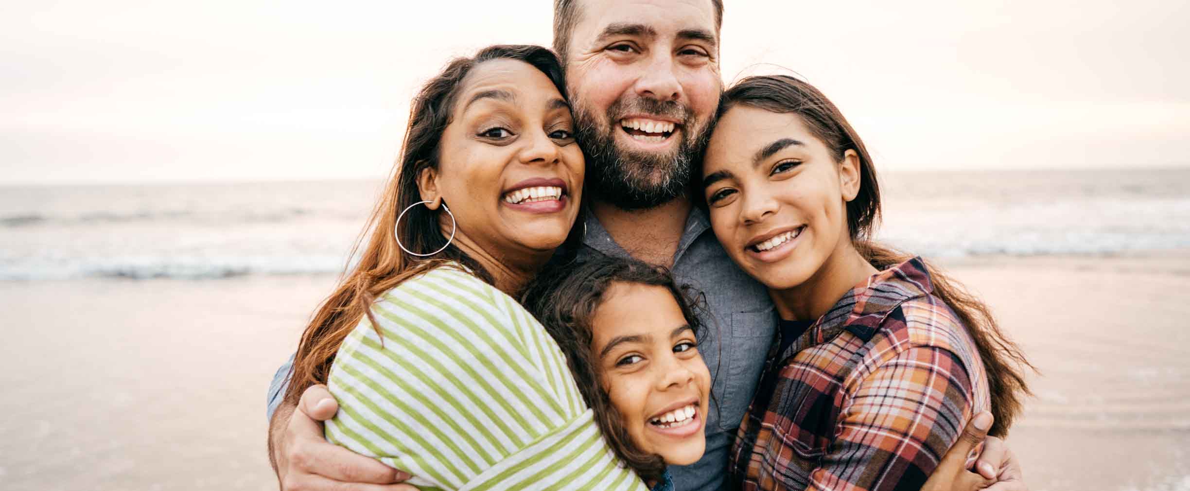 padres sonrientes abrazando a sus dos hijas pequeñas