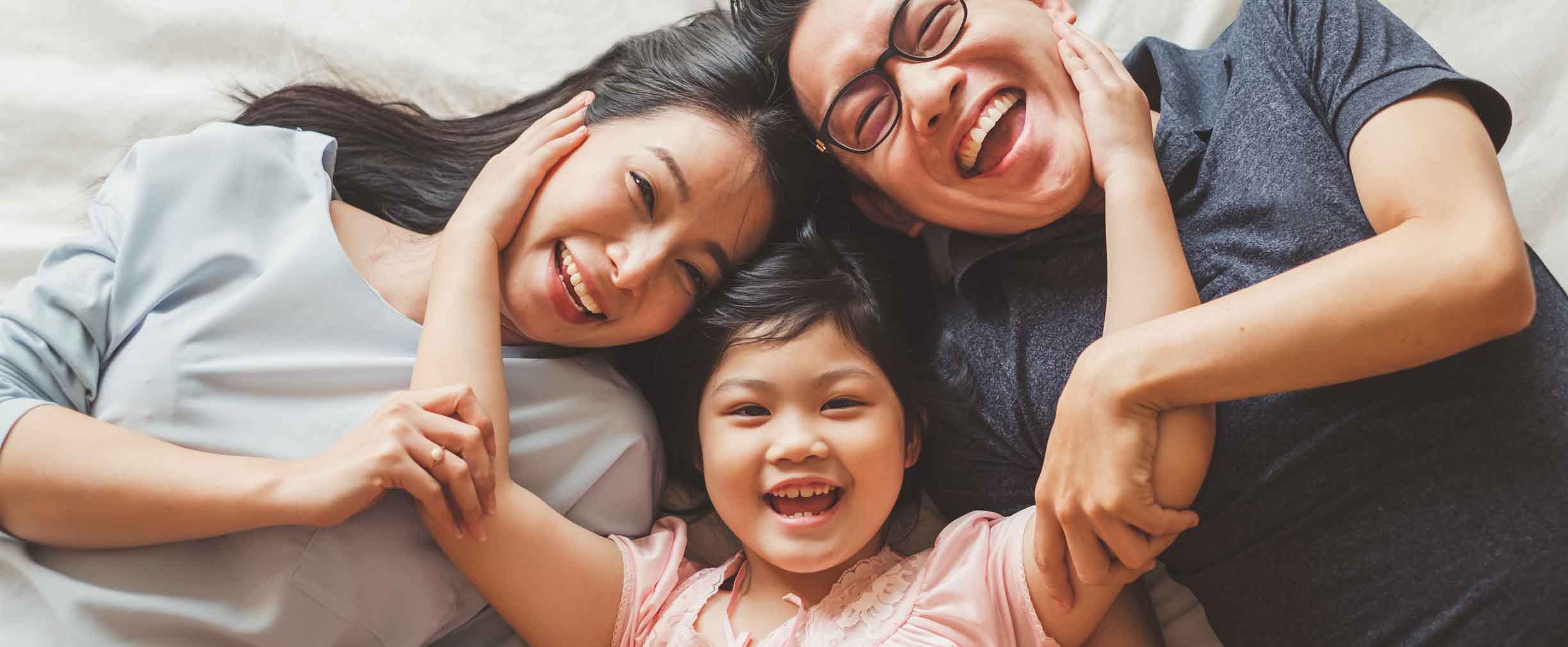 familia feliz en la cama riendo y abrazándose