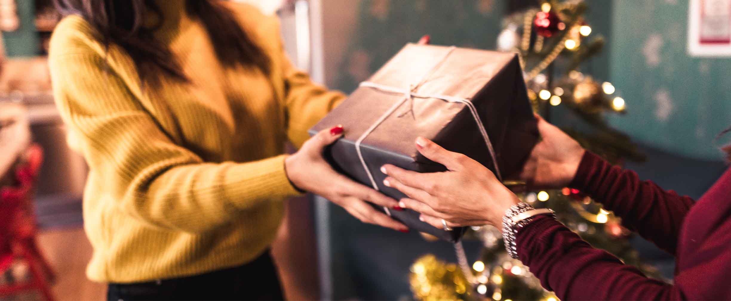 mujer joven recibiendo un regalo de Navidad de un amigo