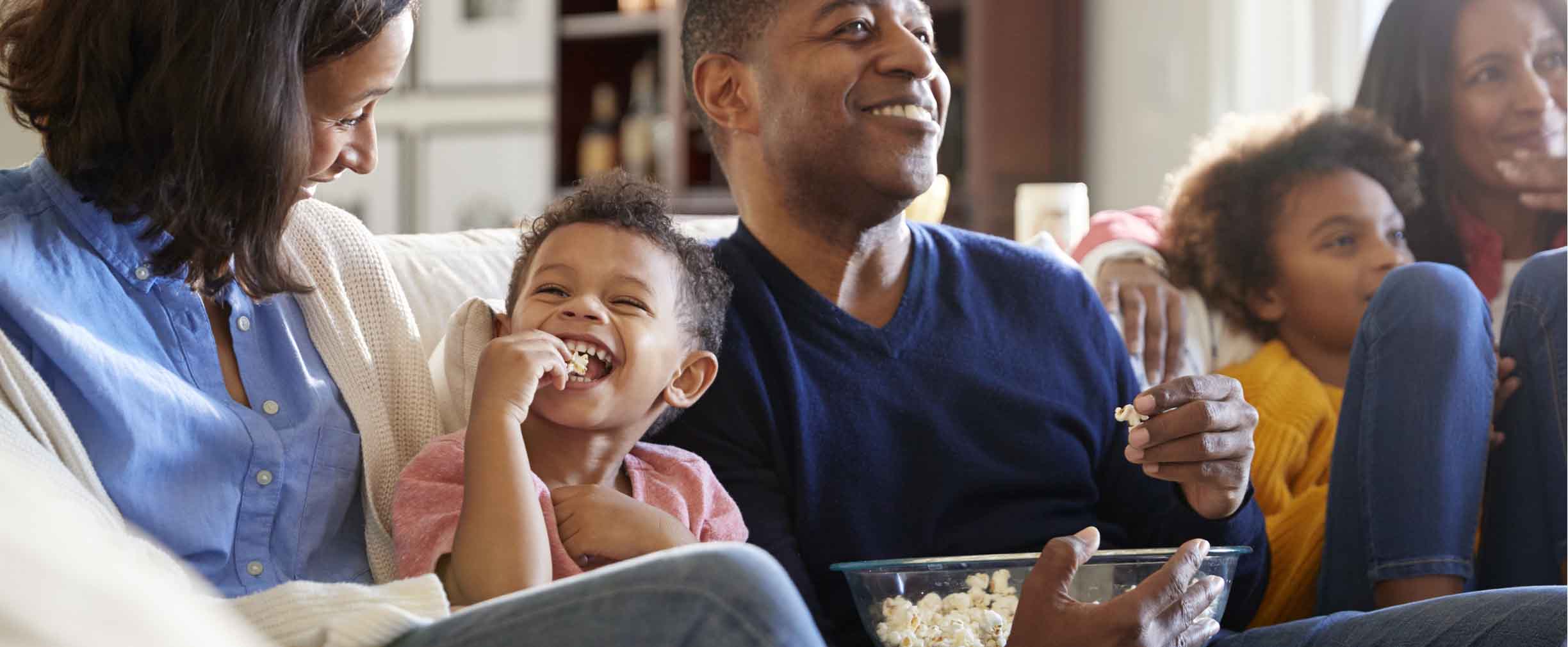 tres generaciones de una familia, felices, mirando una película y comiendo palomitas de maíz