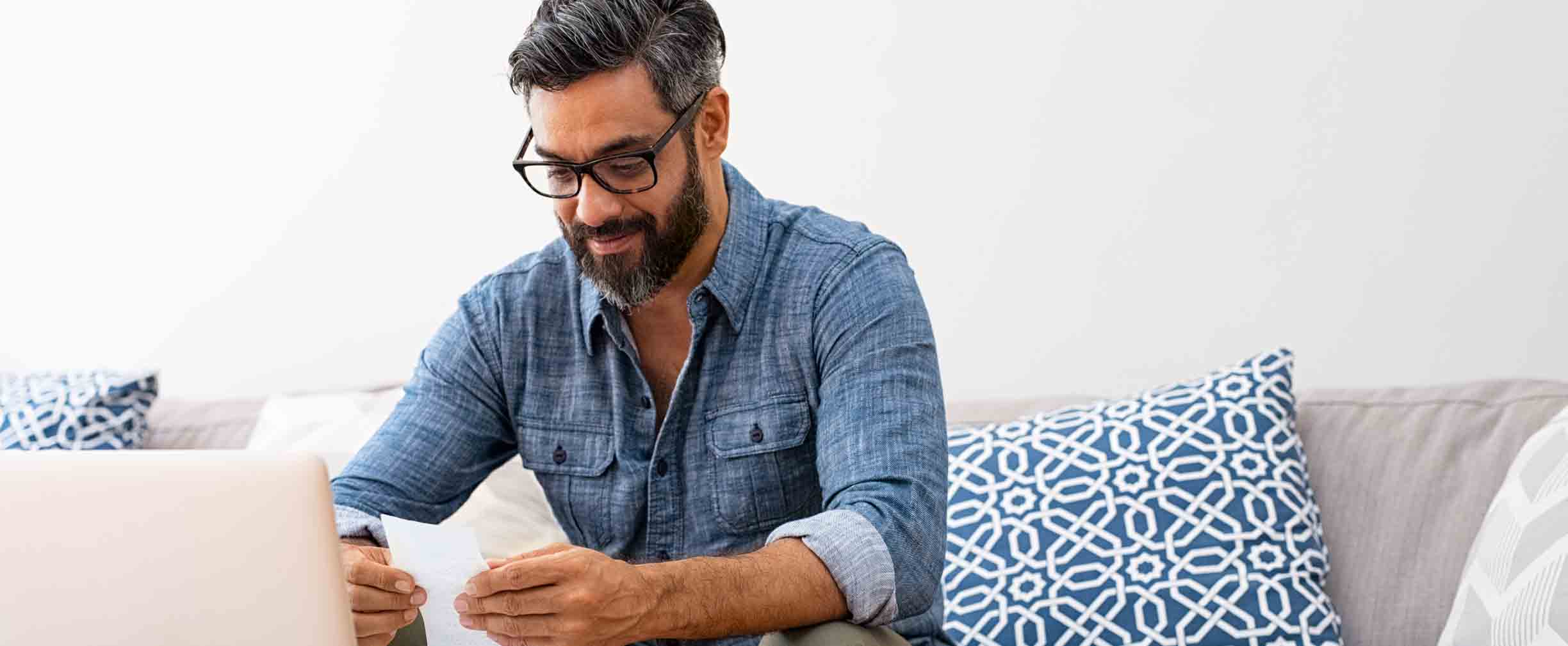 hombre leyendo facturas en su sofá