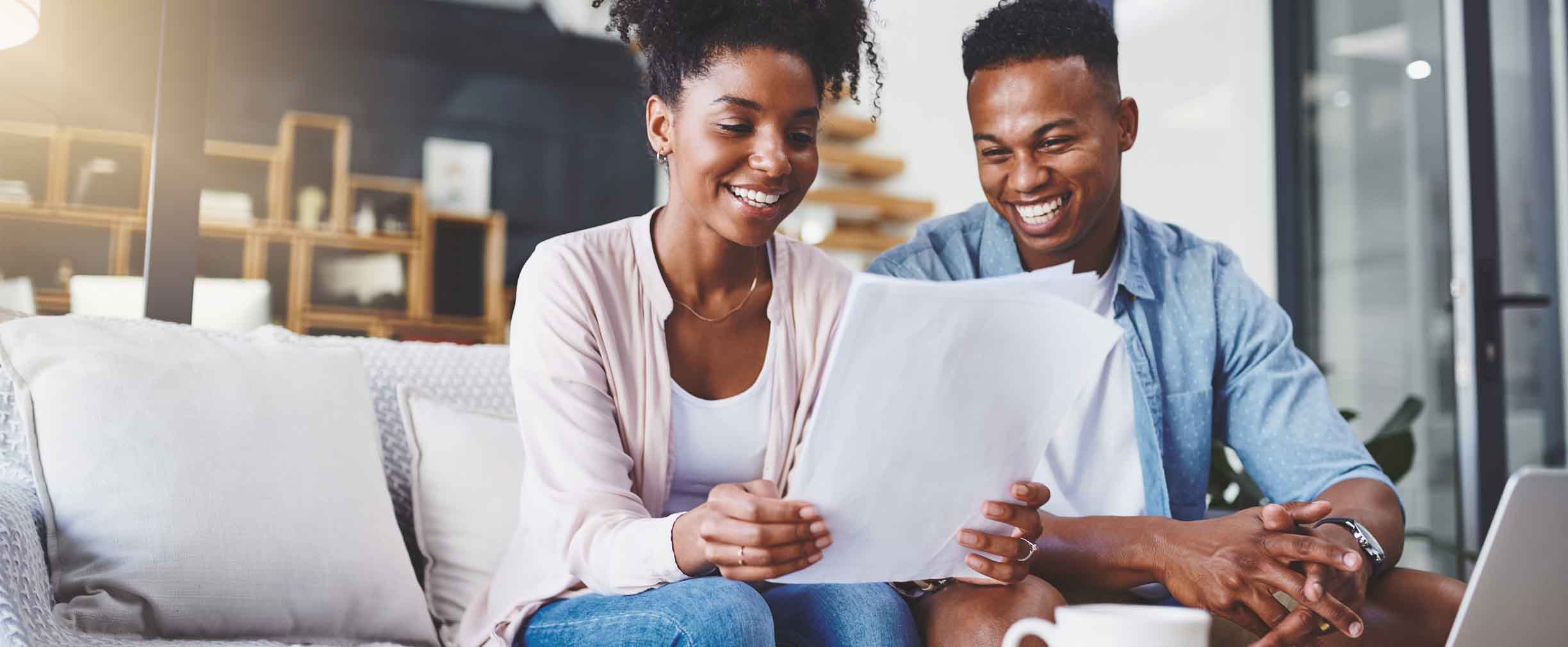 pareja afroamericana sentada en un sofá leyendo documentos