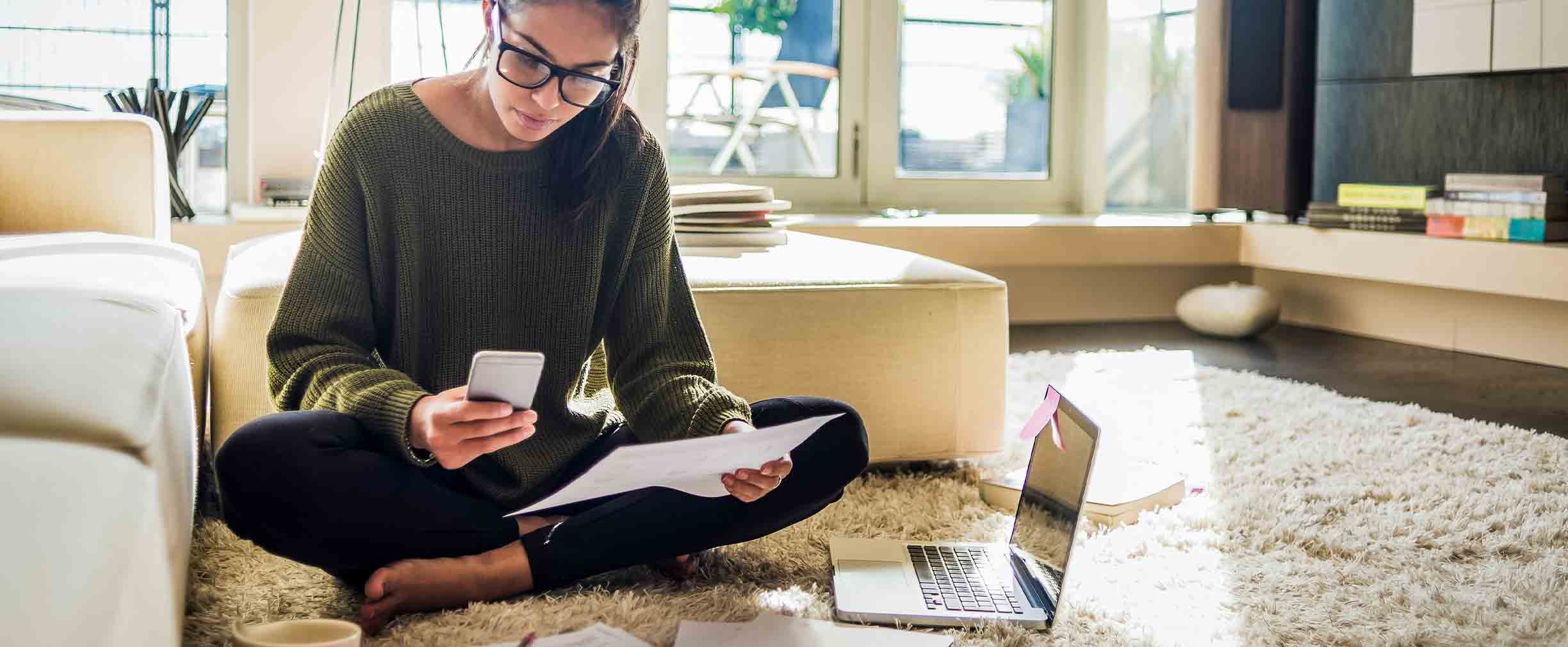 young woman sitting on the floor of her living room and working