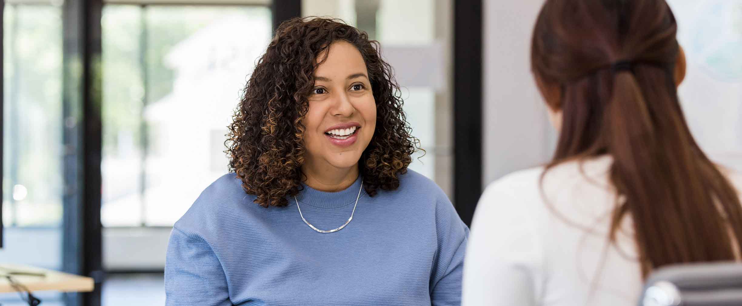 A boss and her employee sit across from one another and discuss a raise.