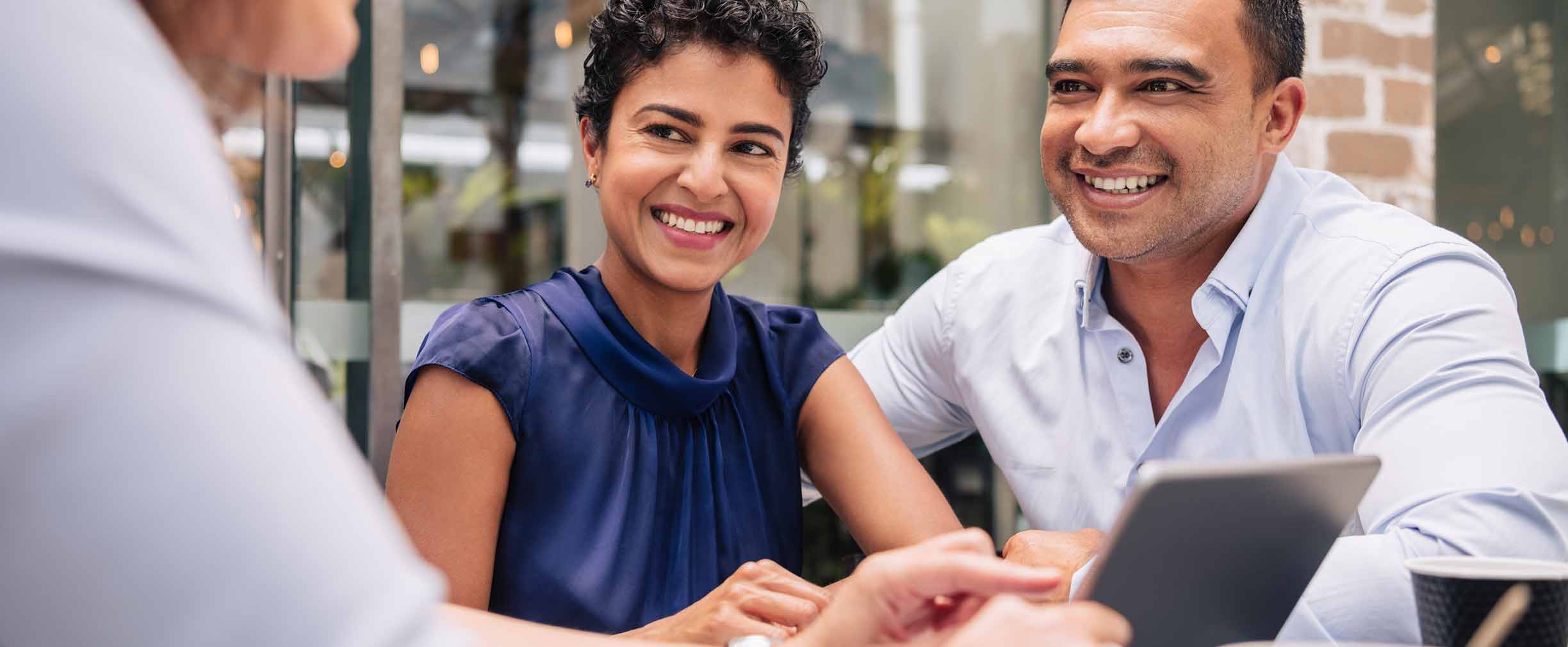 Pareja sonriendo y hablando alrededor de una mesa.