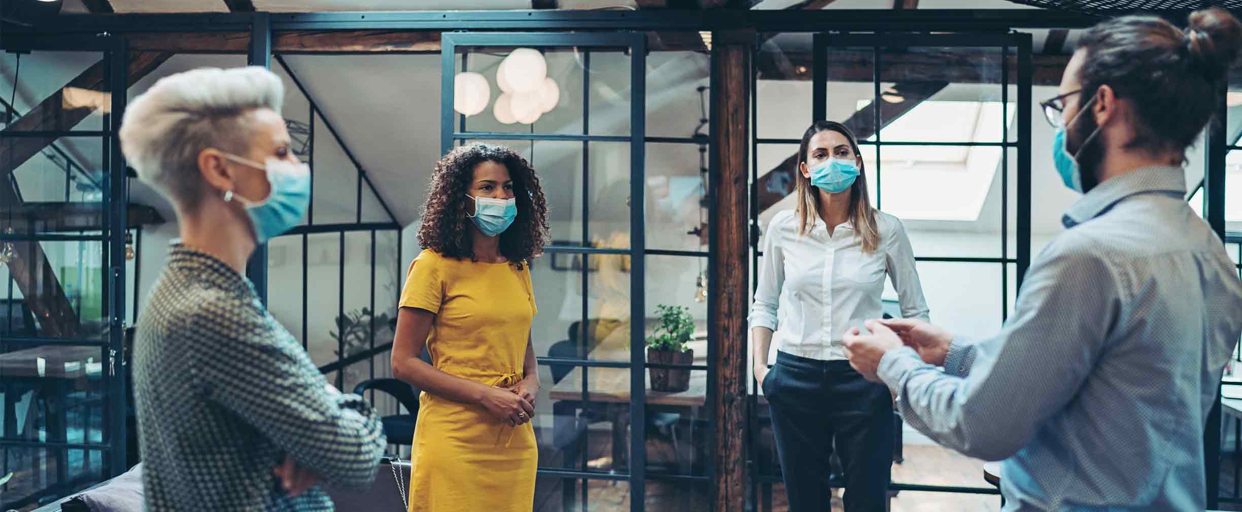 Ejecutivos y ejecutivas con mascarillas en un lugar de uso común en el trabajo