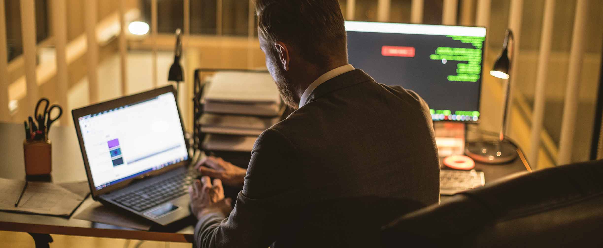 Vista por detrás de hombre usando una computadora por la noche