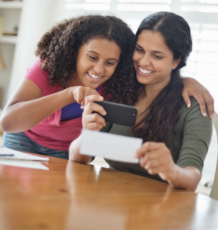 hija ayudando a su madre a depositar un cheque a través de un smartphone