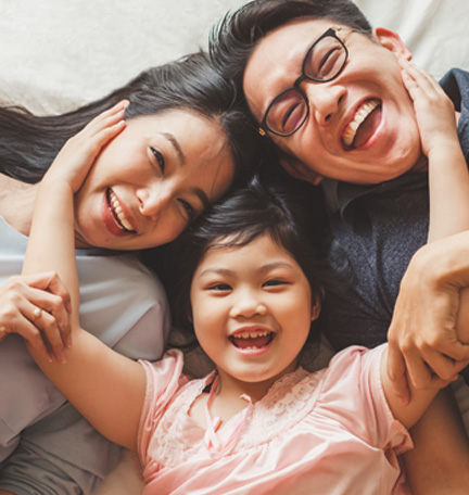 happy family lying on bed laughing and hugging