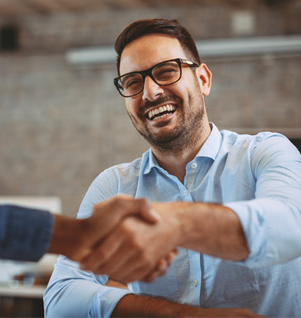 male young professional smiling and shaking hands with a colleague
