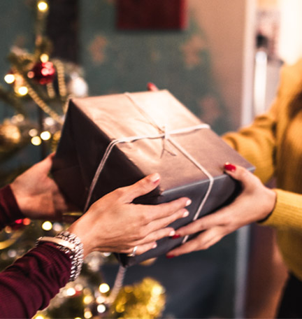 young woman reaching out to receive a Christmas gift from a friend
