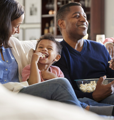 happy three generation family watching a movie and eating popcorn
