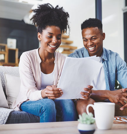 pareja afroamericana sentada en un sofá leyendo documentos