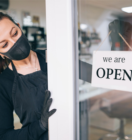 Happy business owner hanging an open sign during COVID-19